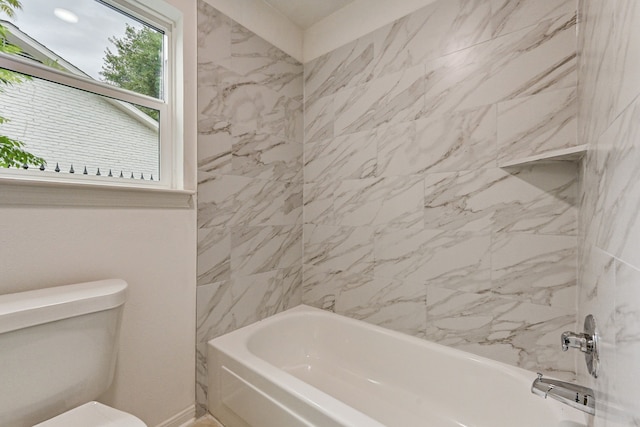 bathroom featuring toilet and tiled shower / bath