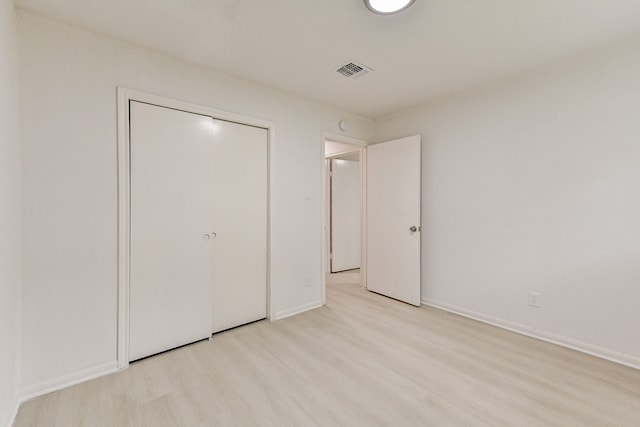 unfurnished bedroom with light wood-type flooring and a closet