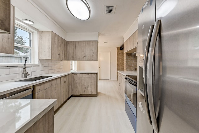 kitchen featuring light hardwood / wood-style floors, appliances with stainless steel finishes, tasteful backsplash, and sink