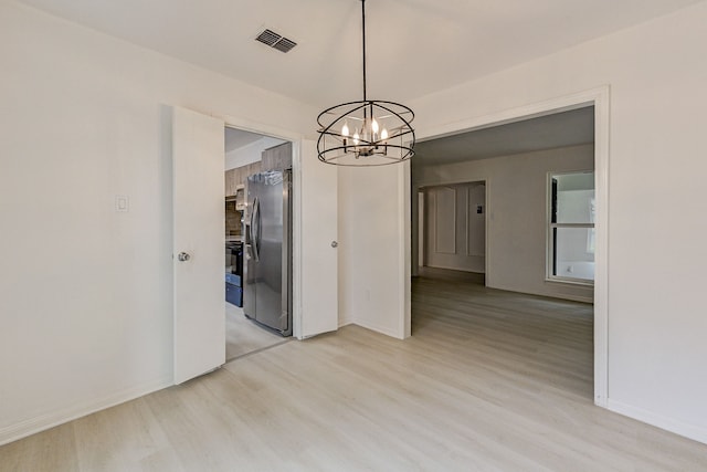 unfurnished dining area featuring light hardwood / wood-style flooring and a chandelier