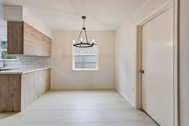 unfurnished dining area with an inviting chandelier, light hardwood / wood-style flooring, and ornamental molding