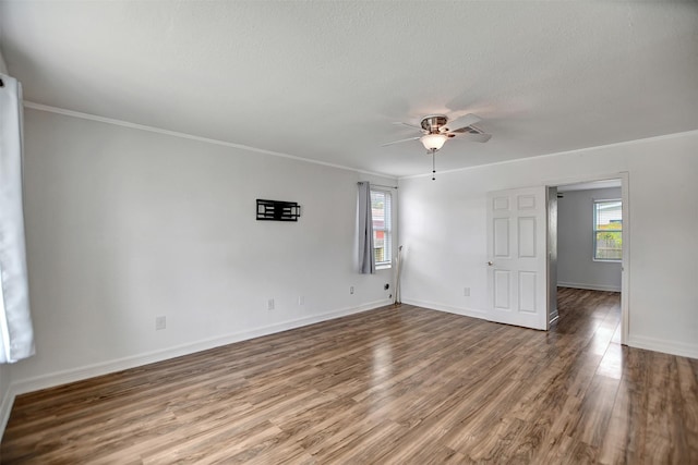 empty room featuring hardwood / wood-style floors, a wealth of natural light, ornamental molding, and ceiling fan