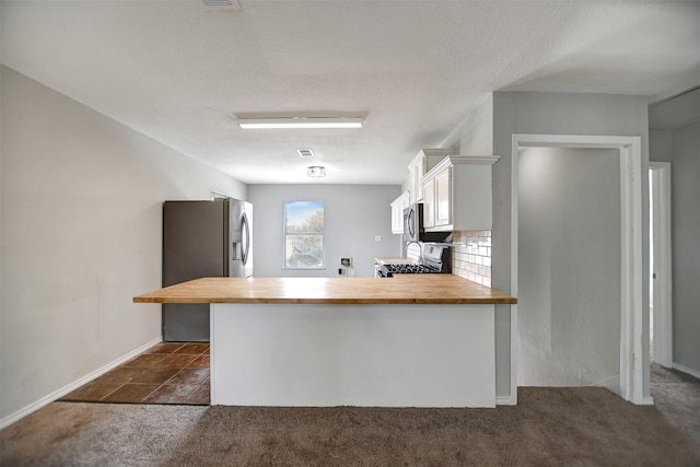 kitchen with wooden counters, appliances with stainless steel finishes, white cabinets, a kitchen bar, and kitchen peninsula