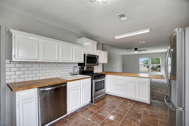 kitchen featuring sink, white cabinetry, wooden counters, appliances with stainless steel finishes, and decorative backsplash