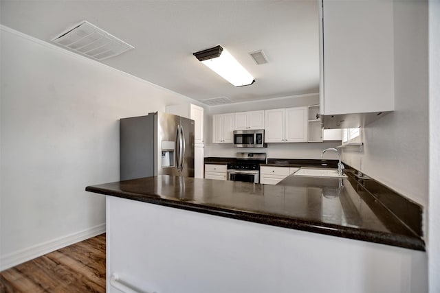 kitchen featuring appliances with stainless steel finishes, white cabinetry, sink, kitchen peninsula, and dark wood-type flooring