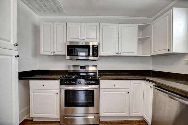 kitchen with white cabinetry, ornamental molding, and stainless steel appliances