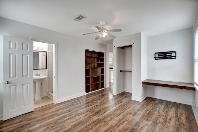 unfurnished bedroom with sink, ceiling fan, hardwood / wood-style floors, connected bathroom, and a barn door