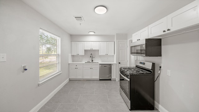 kitchen with light tile patterned flooring, sink, decorative backsplash, white cabinets, and appliances with stainless steel finishes