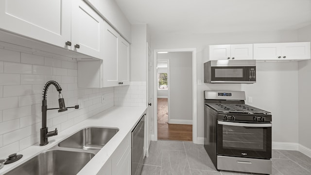 kitchen with light hardwood / wood-style floors, sink, backsplash, white cabinets, and appliances with stainless steel finishes