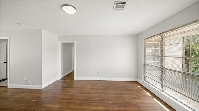 empty room featuring a textured ceiling and dark hardwood / wood-style floors