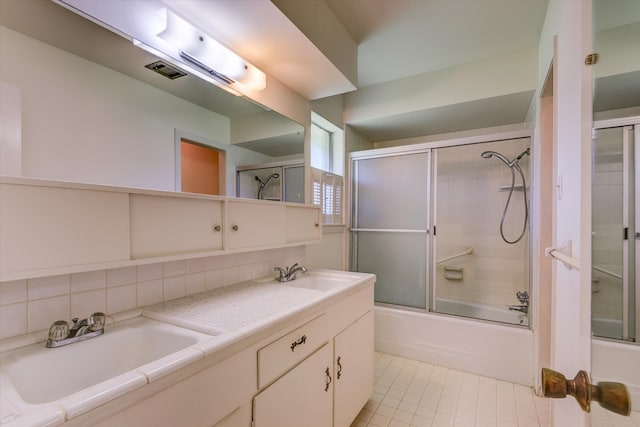 bathroom with vanity, combined bath / shower with glass door, tile patterned flooring, and backsplash