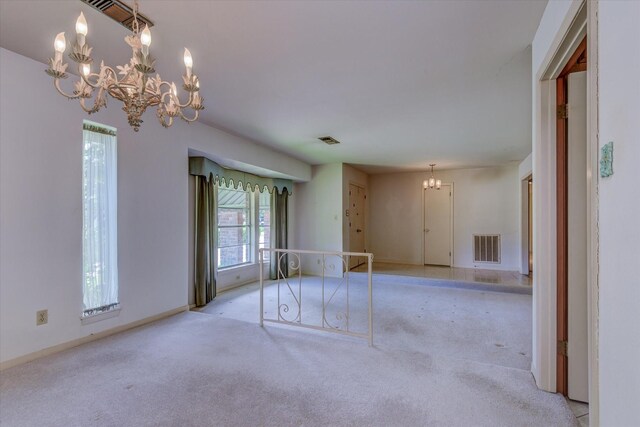 carpeted empty room featuring a notable chandelier