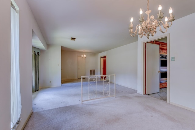 empty room featuring a notable chandelier and light carpet