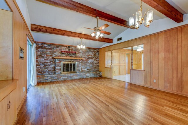 unfurnished living room featuring a fireplace, ceiling fan with notable chandelier, brick wall, and light wood-type flooring