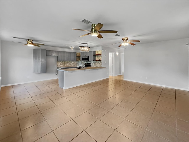 kitchen featuring sink, light tile patterned floors, ceiling fan, tasteful backsplash, and kitchen peninsula