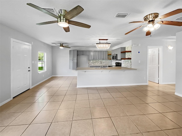 unfurnished living room featuring sink, light tile patterned flooring, and ceiling fan