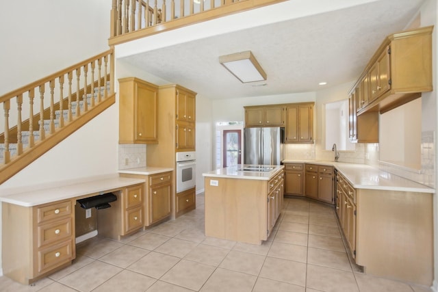 kitchen featuring a center island, light tile patterned floors, white oven, stainless steel fridge, and decorative backsplash