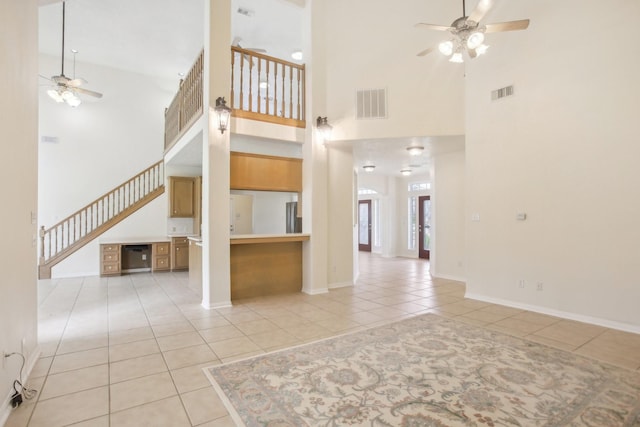 unfurnished living room featuring ceiling fan, a towering ceiling, and light tile patterned floors