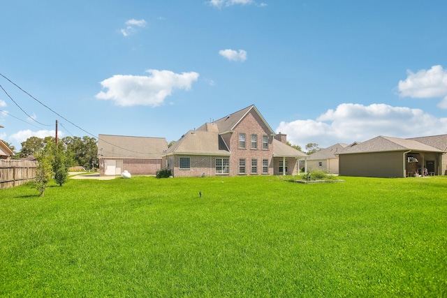 rear view of property featuring a garage and a yard