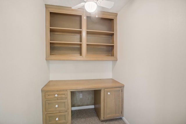 unfurnished office featuring carpet floors, built in desk, and ceiling fan