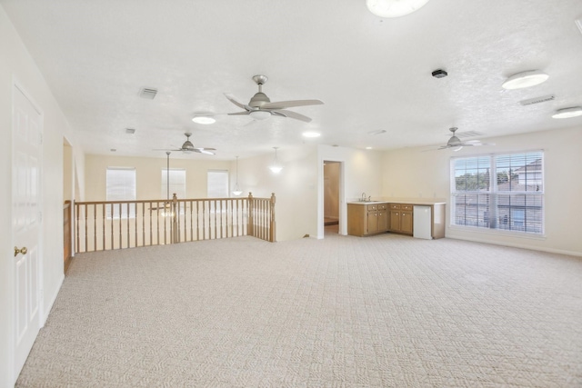 empty room featuring sink, light colored carpet, and a textured ceiling