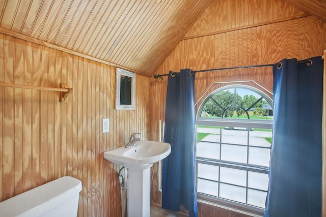 bathroom with lofted ceiling, sink, wood ceiling, wooden walls, and toilet