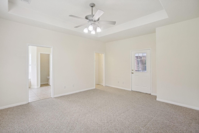 unfurnished room with light colored carpet, ceiling fan, and a tray ceiling