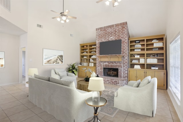 living room featuring ceiling fan, a brick fireplace, and a high ceiling