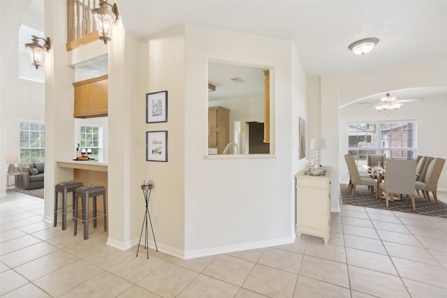 hallway featuring a wealth of natural light, a towering ceiling, and light tile patterned floors