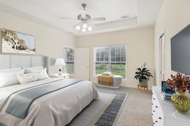 carpeted bedroom featuring a raised ceiling and ceiling fan