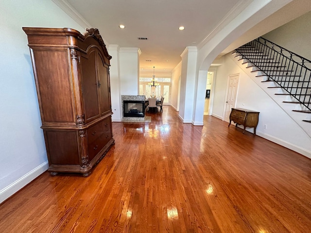 hall featuring crown molding, an inviting chandelier, and dark wood-type flooring