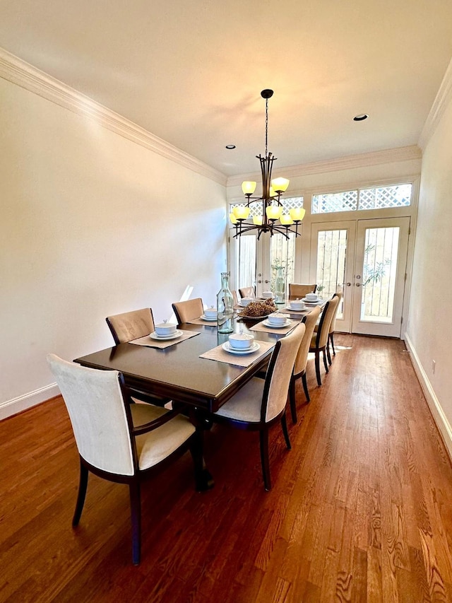 dining area featuring hardwood / wood-style flooring, ornamental molding, a chandelier, and french doors