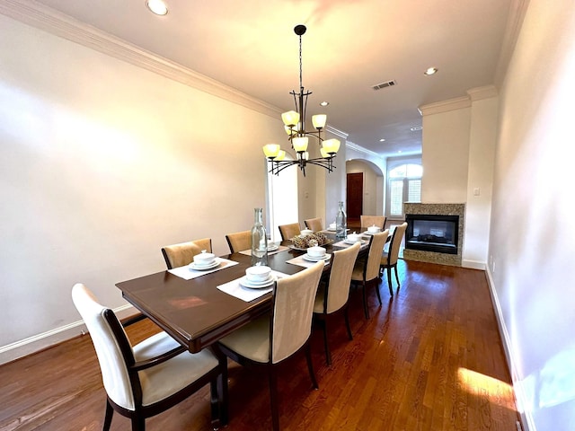 dining area with a notable chandelier, crown molding, dark wood-type flooring, and a multi sided fireplace