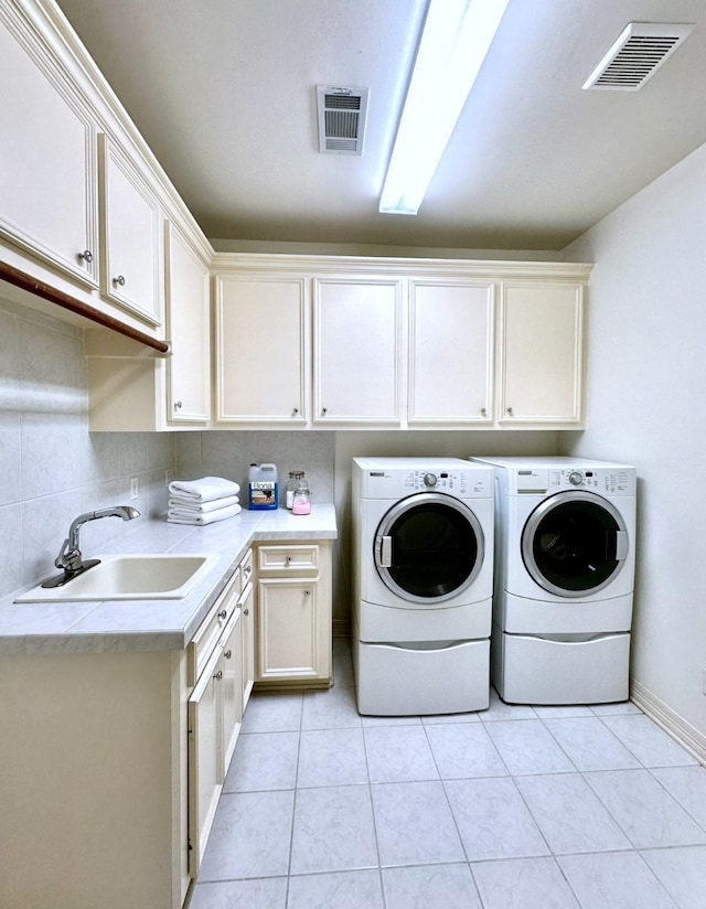 laundry area featuring cabinets, sink, washing machine and dryer, and light tile patterned floors