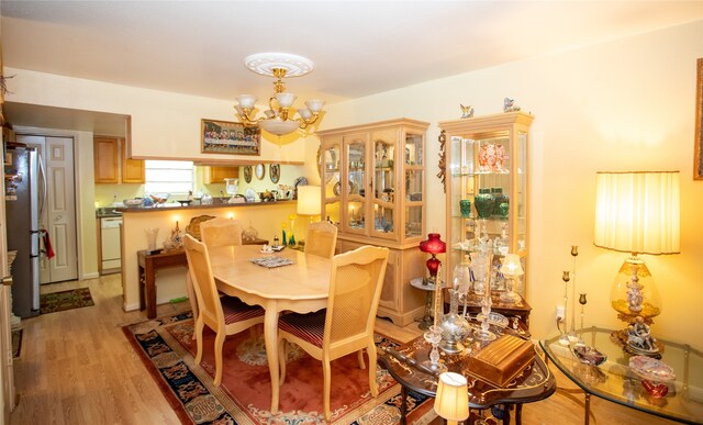 dining room with light hardwood / wood-style flooring and a notable chandelier