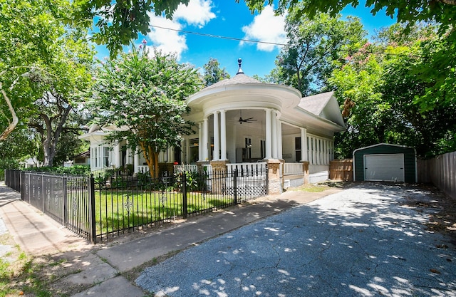 view of front of house with a garage, an outbuilding, a porch, ceiling fan, and a front lawn