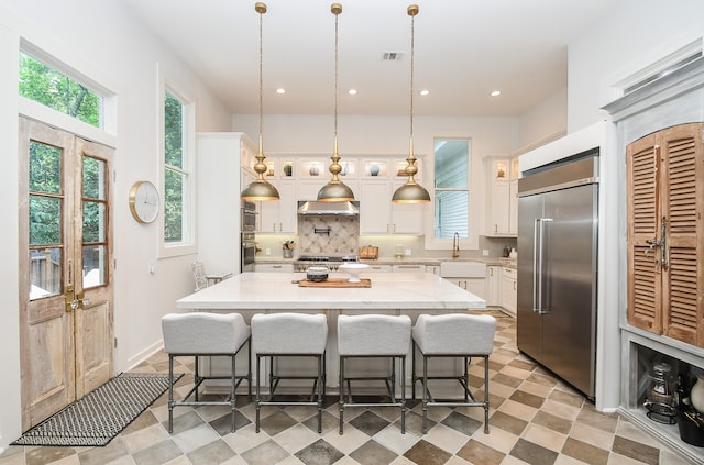 kitchen with white cabinetry, pendant lighting, appliances with stainless steel finishes, light tile patterned floors, and backsplash