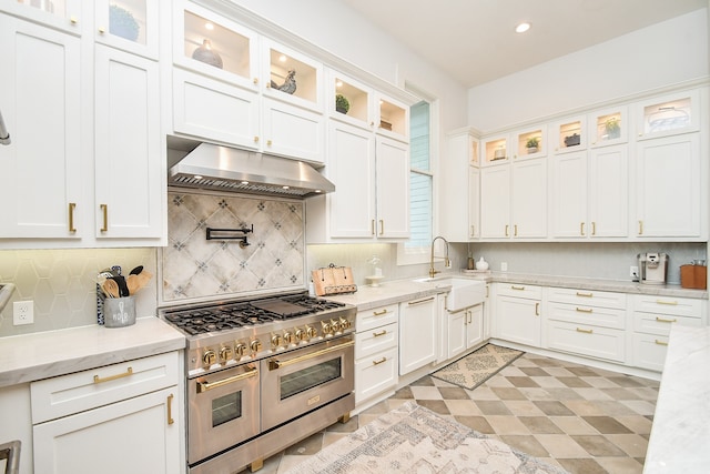 kitchen featuring double oven range, sink, light stone counters, light tile patterned floors, and decorative backsplash