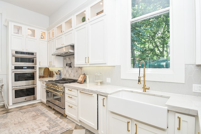 kitchen featuring appliances with stainless steel finishes, light tile patterned flooring, decorative backsplash, and light stone countertops