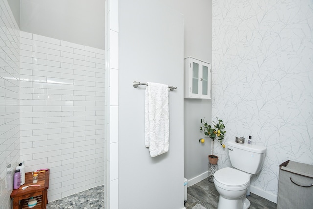 bathroom featuring toilet, a tile shower, hardwood / wood-style flooring, and tile walls