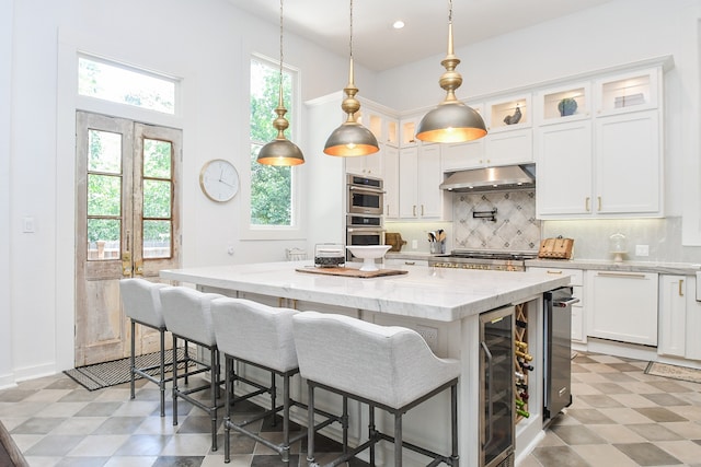 kitchen with light tile patterned flooring, beverage cooler, backsplash, and a center island