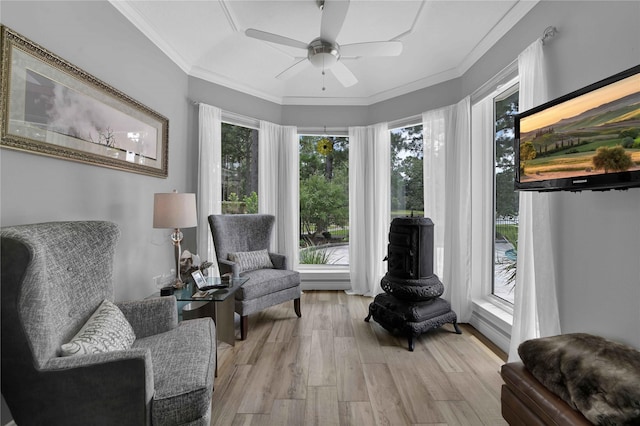 living area with ornamental molding, ceiling fan, and light wood-type flooring