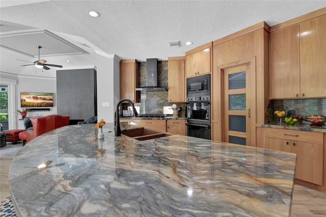 kitchen featuring dark stone countertops, sink, black appliances, and wall chimney exhaust hood