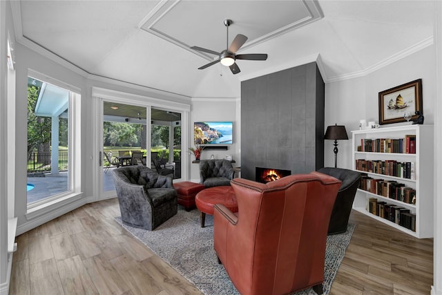 living room featuring crown molding, a large fireplace, ceiling fan, and light wood-type flooring