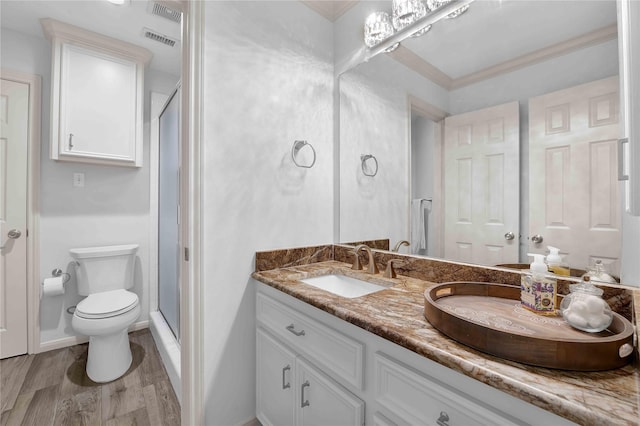 bathroom with wood-type flooring, toilet, vanity, and a shower with shower door