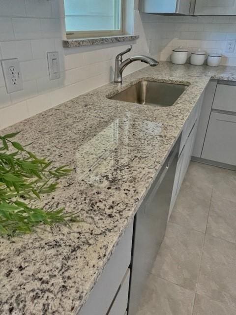 kitchen with light stone countertops, sink, light tile patterned floors, and tasteful backsplash