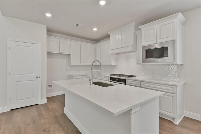 kitchen featuring white cabinetry, an island with sink, and sink