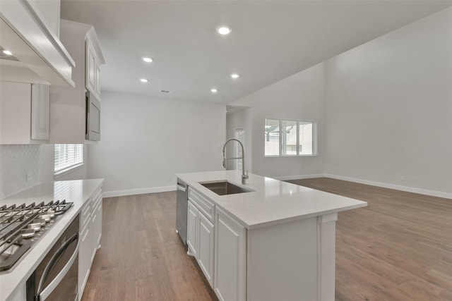 kitchen with sink, white cabinetry, stainless steel appliances, an island with sink, and a healthy amount of sunlight