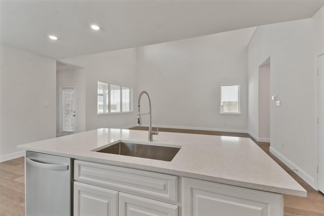 kitchen with sink, light hardwood / wood-style flooring, a kitchen island with sink, white cabinetry, and stainless steel dishwasher