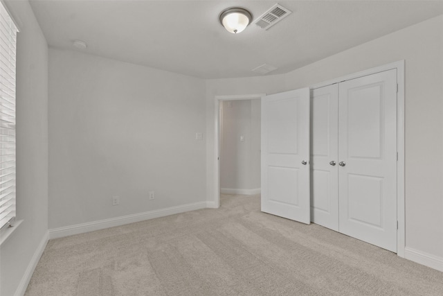 unfurnished bedroom featuring a closet and light carpet